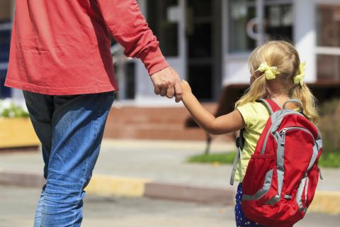 Adulte tenant un enfant par la main pour l'accompagner à l'école